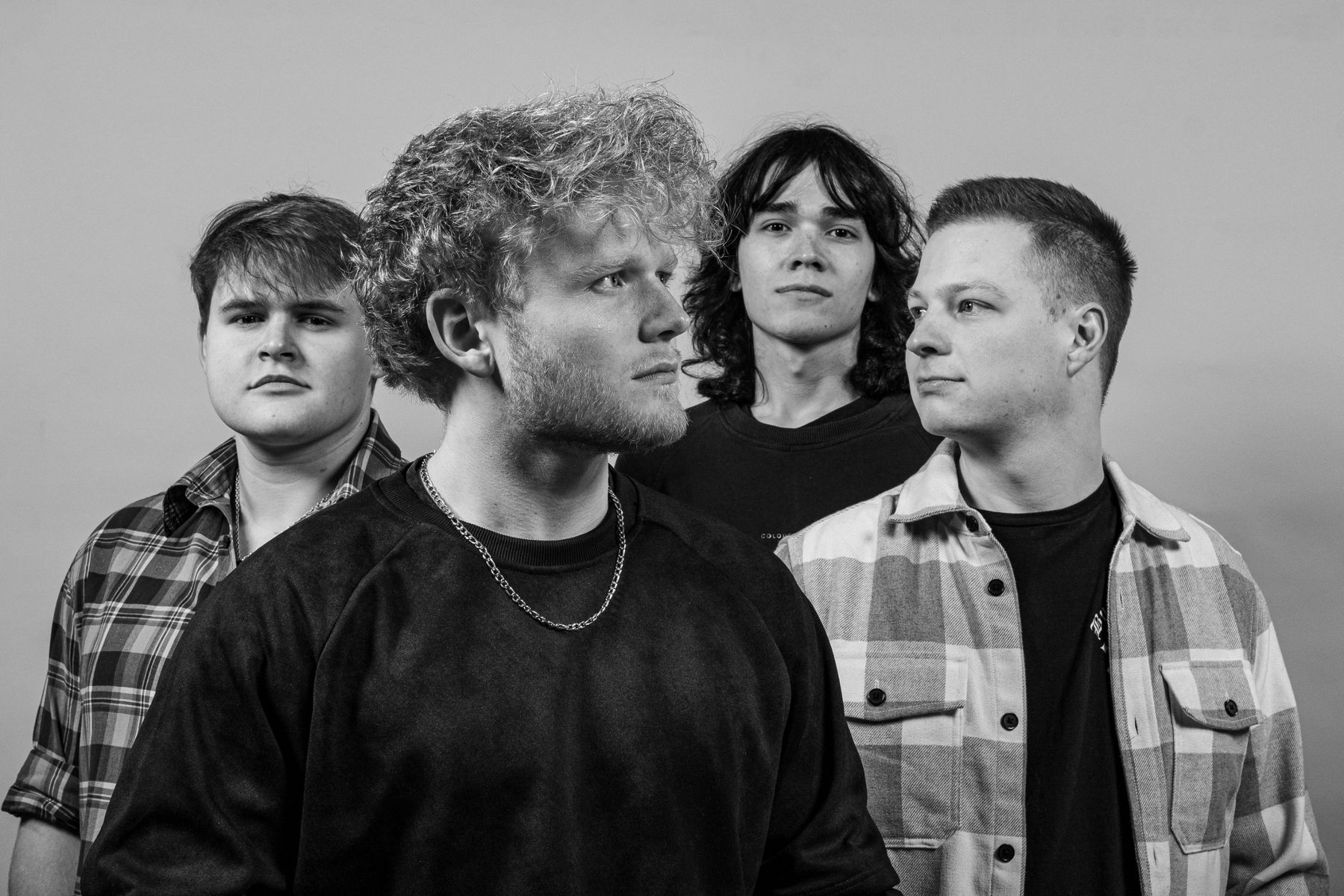 Schwarzweiß-Bandfoto von Purple Trees: Jakob, Jano, Melvin und Ayke vor hellem Hintergrund